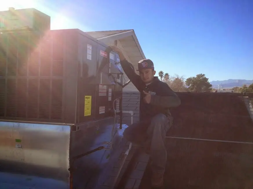 HVAC technician performing AC Tune-Up on a rooftop unit in Bigfork